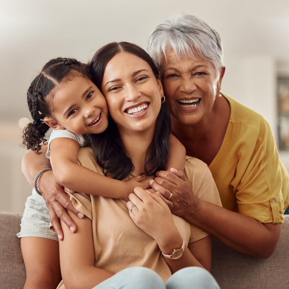 A family sits together on a couch. All three people are smiling.